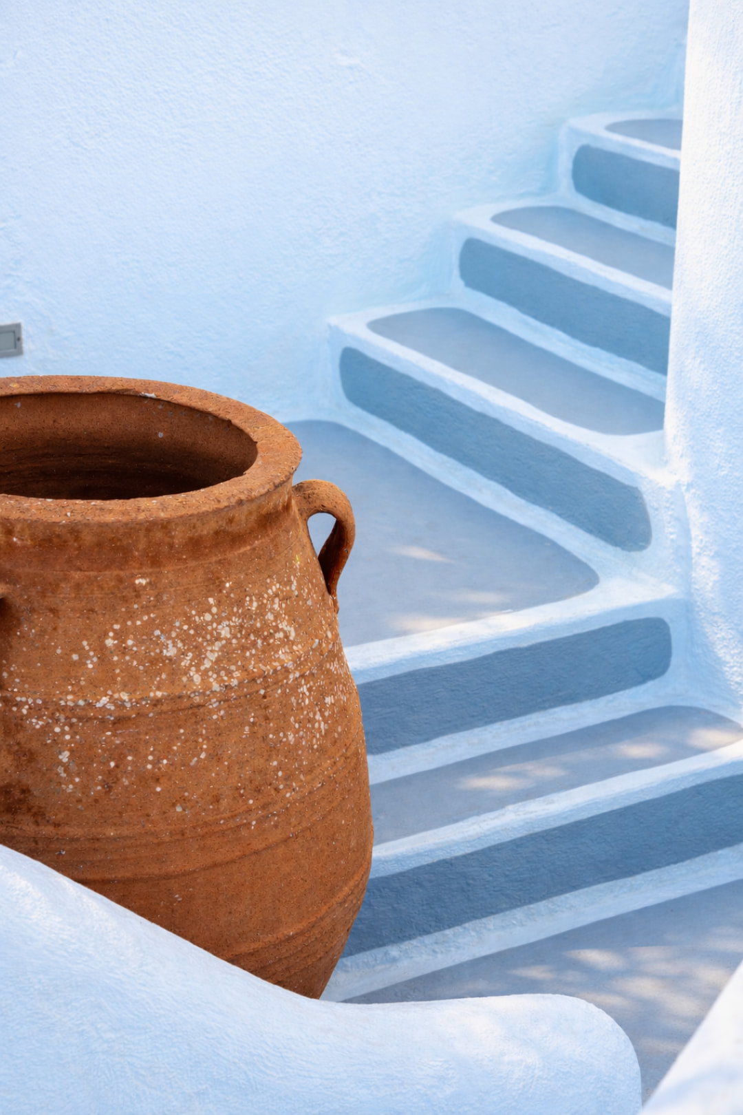 White and blue Cycladic staircase with traditional clay amphora