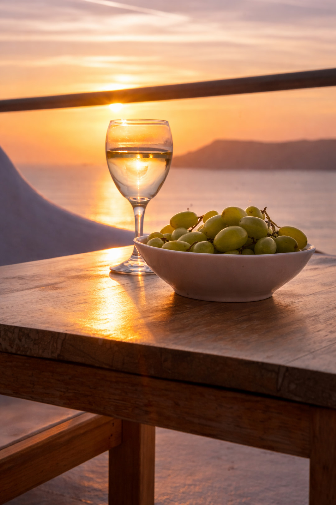 Glass of wine and fresh grapes at sunset on Santorini terrace