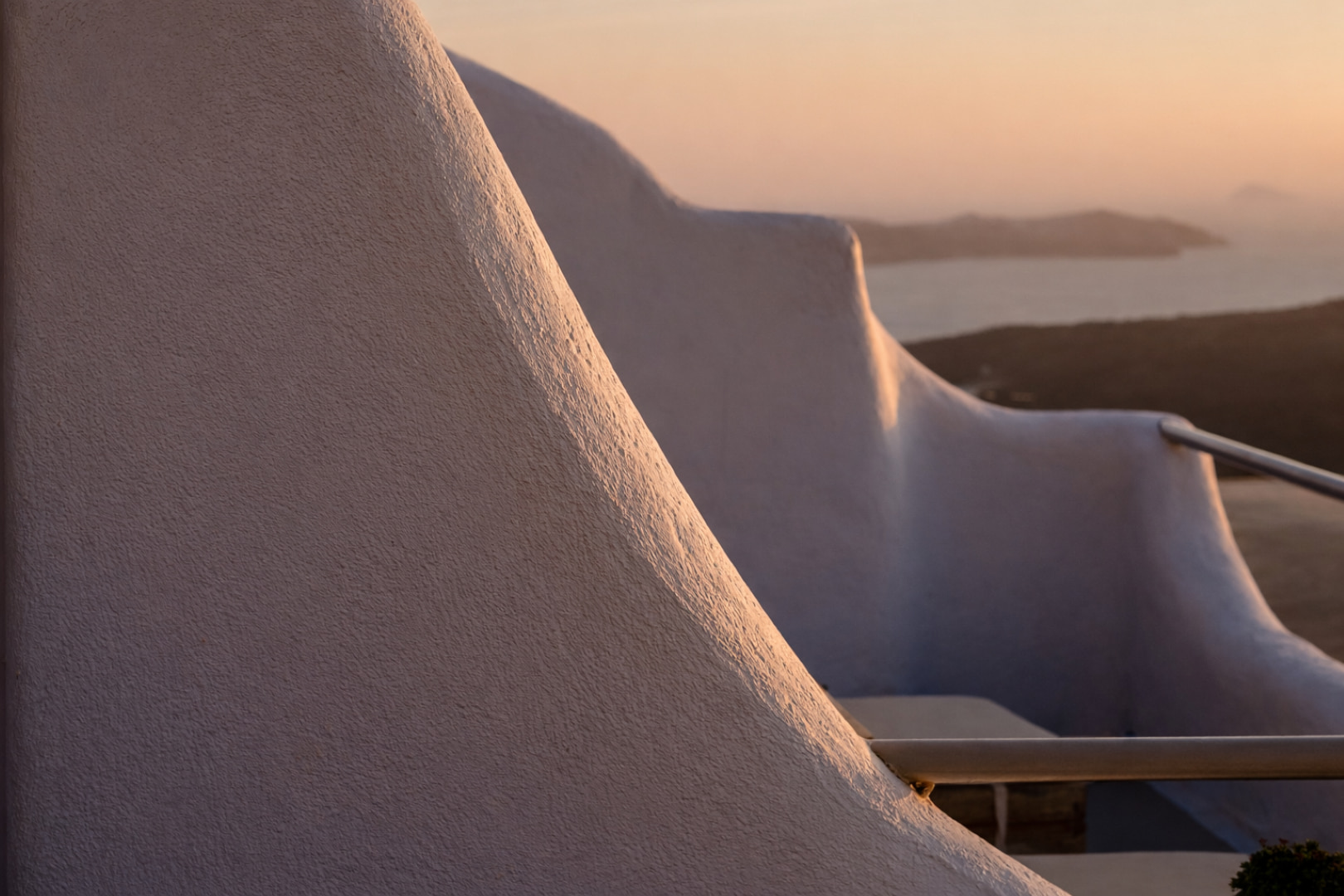 Curved Cycladic architecture glowing at sunset in Santorini
